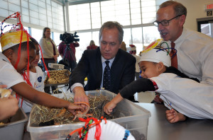 photo -mayor fischer, and chuck denny, with boys and girls playing in tub of toy dinosaurs (?)