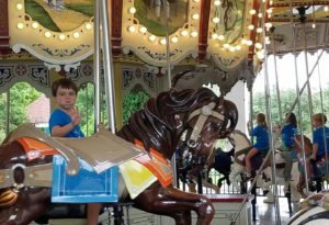 photo - young boy riding an animal on the carousel