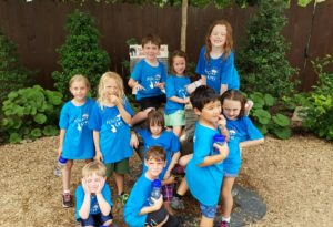 photo - group of day campers, all in blue camper t shirts, sitting on fitz, the elephant statue, by the elephant exhibit