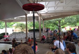 photo - meta zoo stage with a red crown crane, being shown, during hide and seek bird show, with kids, adults watching from the meta zoo amphitheater seating