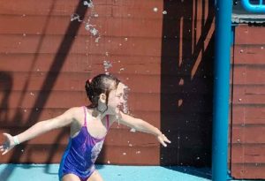 photo - young girl, playing among water spouts, while in zoo splash park