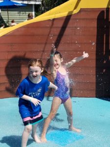 photo - 2 young children, in swim suits, playing with inground water spouts, in zoo splash park