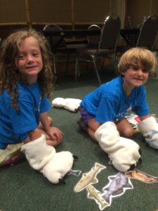photo - Safari day campers, trying on polar bear paws, to show how big they get, plus some examples of fish that polar bear may enjoy eating.