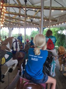 photo - Safari day campers riding the zoo carousel with counselors