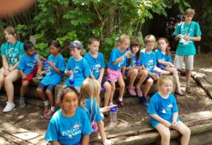 photo - zoo day campers, blue t shirts, with counselors, sitting in shade, trying to cool off in the hot weather