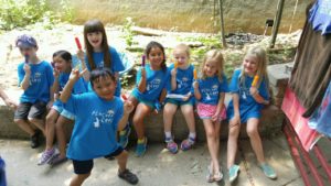 photo - zoo day campers, boys and girls, in blue t-shirts, having popsicles on hot summer day, sitting on stone wall