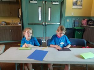 photo - 2 young zoo day campers, working with colored papers, pencils, on how to make elephants for zoodunnit class