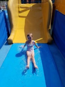 photo - young girl, in swimsuit, sliding down yellow water slide, at zoo splash park