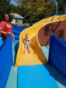 photo - young girl, in swimsuit, sliding down yellow water slide, in zoo splash park water park