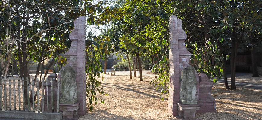 photo - cover islands, with archway w/stone pillars, asian stone figures at each, with background of green trees, on a sunny day