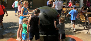 photo - the water ball, located on main inside plaza of zoo, with variety of kids turning the ball, or trying to stop the turning ball, which you can't do, plus tables and chairs for guests to sit, rest or eat lunch, on a sunny summer day