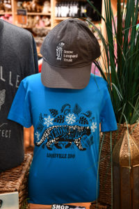 photo - blue zoo t shirt with Strong, Fearless, Louisville Zoo print on front, ball cap for snow leopard trust with image of snow leopard on cap