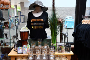 photo - variety of gift shop items to purchase - drums, glasses, t shirts, w/live, wild, free on front, post cards, stickers, carved animal items, hats, animal pins