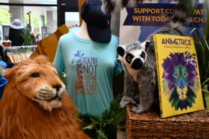 photo - variety of gifts you can purchase at zoo gift shop, zoo t shirts, variety of plush animals, lemurs, lions, ball caps, informational books about zoo animals