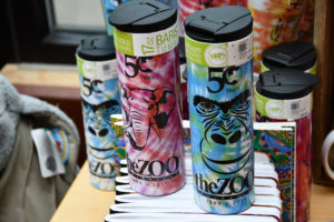 photo - 50th anniversary different colored tumblers for sale at gift shop, with different animal designs on tumblers, theZOO logo on them also