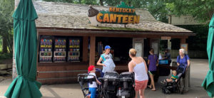 photo - main front plaza Ky Canteen selling refreshments, showing icee machines, variety of visitors with stroller, babies, kids, chking out menu, purchasing snacks ,