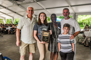 photo - John Walczak, Diane Taylor with young girl volunteer, holding Heaton award, who won it, with other family members
