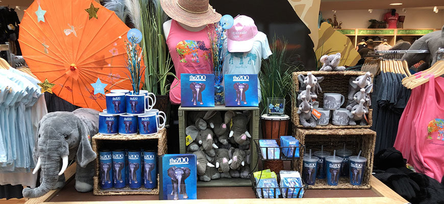 photo - Gift shop display of Fitz the elephant souvenirs that visitors can purchase, coffee cups, water bottles, t-shirts, stickers, book, plush animals, hats, post cards, drink cup, summer Ts