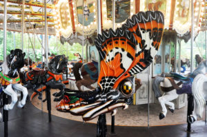 photo - carousel insect ride monarch orange, black,, white butterfly, with variety of other animal rides in the background