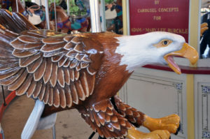 photo - carousel animal ride white headed bald eagle, with brown wings, body feathers, yellow talon feet, yellow open beak