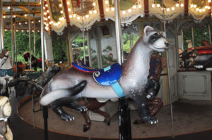 photo - carousel animal ride of grey ferret with blue saddle, background are some other animal rides