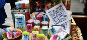 photo - gift shop display of zoo souvenirs you can purchase, coffee cups, cold/hot beverage drink cups, stickers, notebooks, drink cups, with gorilla images on most of the sourvenirs, variety of colors for the items being sold