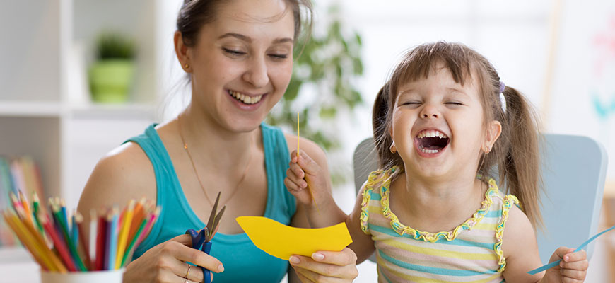 photo - mom and child, laughing while doing arts and crafts at meta zoo, cutting out animals, color with colored pencils