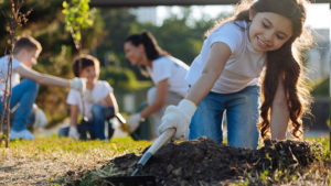Girl digging in soil and planting - Community initiatives