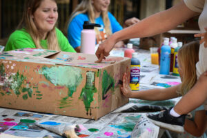 photo of zoo workers doing arts and crafts, painting boxes, with children