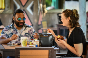 photo of two zoo visitors , eating lunch at outpost (?)