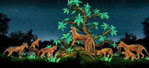 banner - scene of 8 Thylacine animals, orange color fur with black stripes down back with long tail, standing around tree with branches of green leaves, in field, surrounded with trees and bushes with night time sky with stars