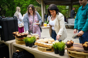 photo of visitors having breakfast of muffins, donuts, orange juice, with variety of seedlings displayed at monarchs-mimosas event, 2023