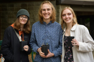 photo of 3 visitors showing off their seedlings they were taking home at monarchs -mimosas event 2023