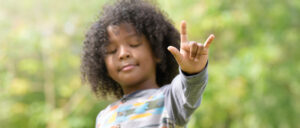 photo of child displaying sign language sign during Deaf and Hard of Hearing Awareness Day.
