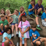 photo - variety of zoo campers kids, sitting on and around rhino statue