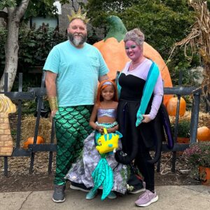 Family at Boo at the Zoo in front of Mumpkin dressed as King Triton, Ursula and Ariel.